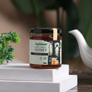 A jar of Deep Forest Honey with a label showing the brand name and the product name, placed on a white surface, with a white decorative object and greenery in the background.
